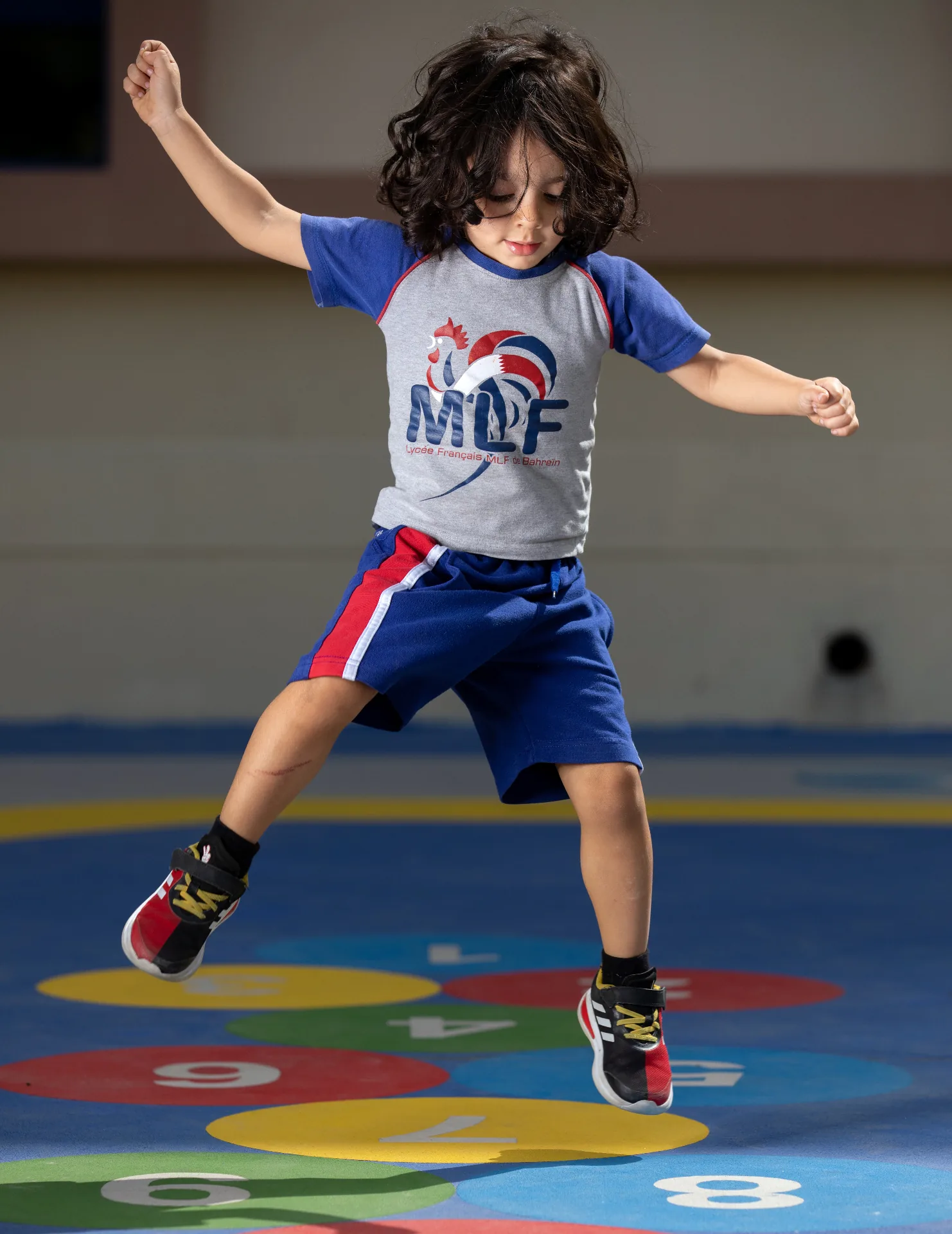 طالب من المدرسة يقفز في الصالة الرياضية فوق دوائر ملوّنة مرقّمة